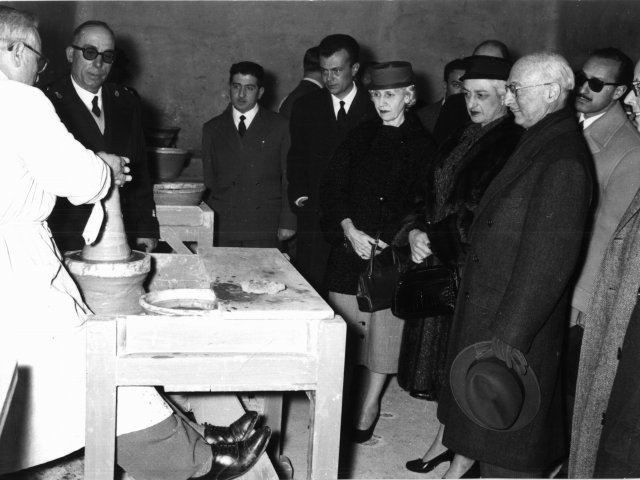 Visita Ambasciatore Zellerbach - L’Ambasciatore Zellerbach, la sua consorte ed altri membri dell’Ambasciata, nell’aula di foggiatura. Al tornio il prof. Vincenzo Spagnulo; da destra in prima fila, l’Ambasciatore, la consorte, due rappresentanti dell’Ambasciata e il Direttore Angelo PelusScarica il file