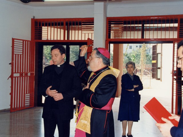 Visita e benedizione della scuola da parte di SE Mons Benigno Papa - L’Arcivescovo di Taranto Mons. Benigno Papa, nell’androne d’ingresso della scuola, inizia la benedizione. Al suo fianco Don Salvatore Ligorio, dietro, Grazia Occhibianco. In primo piano un sacerdote accompagnatore dell’Arcivescovo.Scarica il file